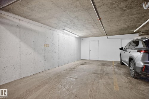 Private parking space featuring concrete walls and flooring, overhead lighting, and exposed piping - 215 1080 Mcconachie Boulevard, Edmonton, AB - Indoor Photo Showing Garage