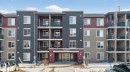 The property features a multi-story building with a facade incorporating dark stone-look cladding and lighter colored siding - 215 1080 Mcconachie Boulevard, Edmonton, AB  - Outdoor With Balcony With Facade 