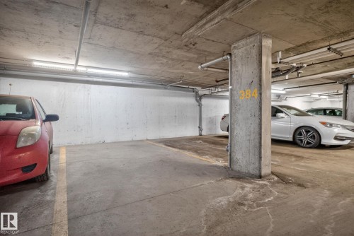 Dedicated parking space within a subterranean parking structure, featuring overhead lighting and concrete walls and ceiling - 215 1080 Mcconachie Boulevard, Edmonton, AB - Indoor Photo Showing Garage