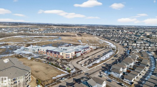 Aerial view showcasing a residential area with varied housing styles and a prominent community building - 215 1080 Mcconachie Boulevard, Edmonton, AB - Outdoor With View