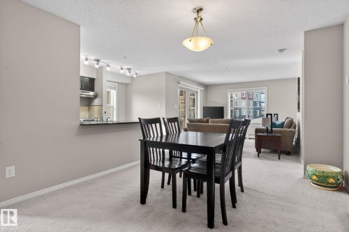 This interior features carpeted flooring, light-toned walls, and a ceiling light fixture - 215 1080 Mcconachie Boulevard, Edmonton, AB - Indoor Photo Showing Dining Room