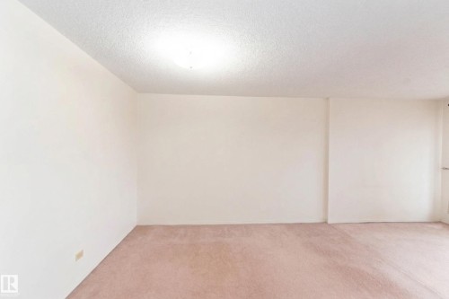 Spacious room featuring light-colored walls, a textured ceiling, and soft carpet flooring - 1004 11027 87 Avenue, Edmonton, AB - Indoor Photo Showing Other Room