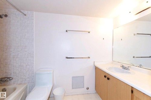 Bathroom featuring a vanity with a white countertop and a mirror, a toilet, and a bathtub with tiled walls - 1004 11027 87 Avenue, Edmonton, AB - Indoor Photo Showing Bathroom