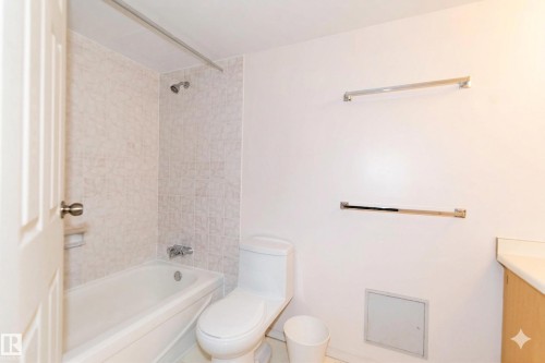 Bathroom featuring a white bathtub with a shower, a toilet, and light-colored vanity with a countertop - 1004 11027 87 Avenue, Edmonton, AB - Indoor Photo Showing Bathroom