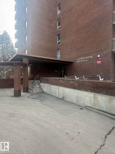 The property features an entryway with brick columns and an overhead awning, leading to steps and a paved surface - 1004 11027 87 Avenue, Edmonton, AB - Outdoor