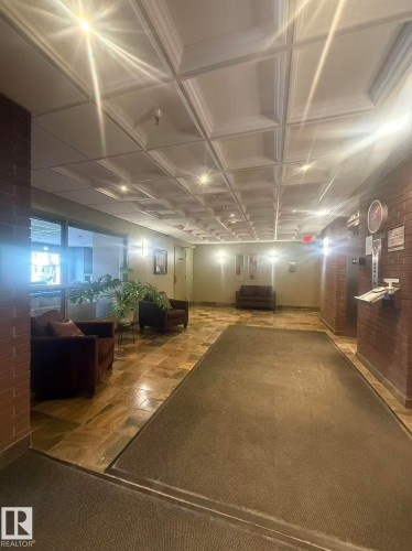 The property features a common area with recessed lighting, a coffered ceiling, and brick accent walls - 1004 11027 87 Avenue, Edmonton, AB - Indoor
