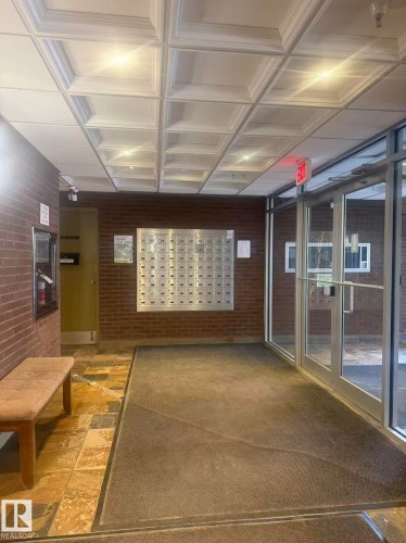 The building entrance features a brick wall, a tiled floor, and a coffered ceiling with recessed lighting - 1004 11027 87 Avenue, Edmonton, AB - Indoor Photo Showing Other Room