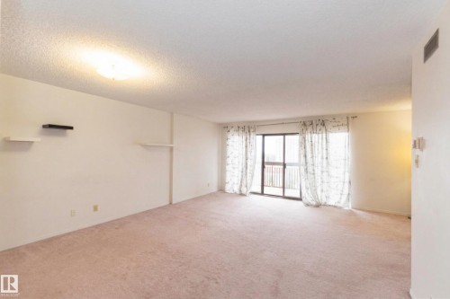 Expansive room featuring light-colored carpet, white walls, and a ceiling light fixture - 1004 11027 87 Avenue, Edmonton, AB - Indoor Photo Showing Other Room