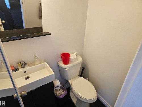 Bathroom featuring a wall-mounted mirror with a shelf, a rectangular sink with a faucet, and a toilet - 844 Erin Place, Edmonton, AB - Indoor Photo Showing Bathroom