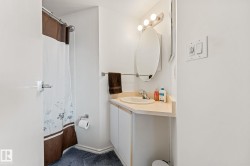 The bathroom features a vanity with a countertop and sink, an oval mirror, and a shower area - 