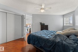 The bedroom features hardwood flooring, a ceiling fan with integrated lighting, and a window with horizontal blinds - 
