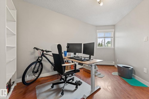 This bright room features a window with horizontal blinds, light-colored walls, and hardwood flooring - 208 6710 158 Avenue, Edmonton, AB - Indoor Photo Showing Office