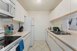 Efficient kitchen featuring white cabinetry, a double basin sink, and white appliances - 