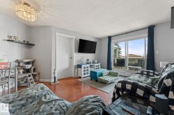 The living area features hardwood flooring, light grey walls, and a sliding glass door leading to an outdoor space - 