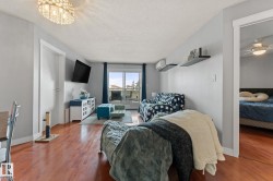 Living area featuring hardwood flooring, a decorative chandelier, and access to an outdoor balcony - 