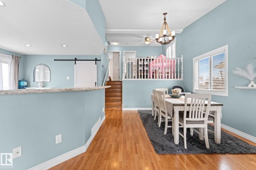 The dining area features hardwood floors, a large window with blinds, and a chandelier - 7252 152C Avenue, Edmonton, AB - Indoor Photo Showing Dining Room