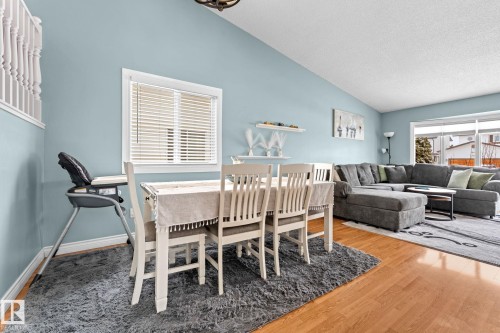 This inviting living space features light blue walls, hardwood flooring, and a dining area with a window providing natural light - 7252 152C Avenue, Edmonton, AB - Indoor Photo Showing Other Room