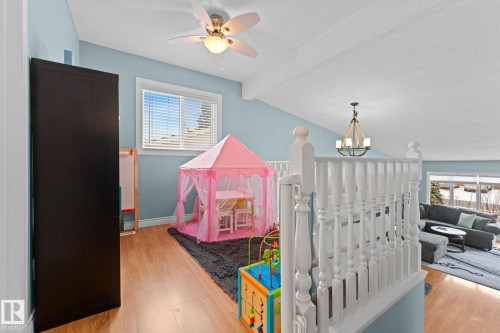 This bright loft area features hardwood flooring, a ceiling fan, and a window with blinds - 7252 152C Avenue, Edmonton, AB - Indoor