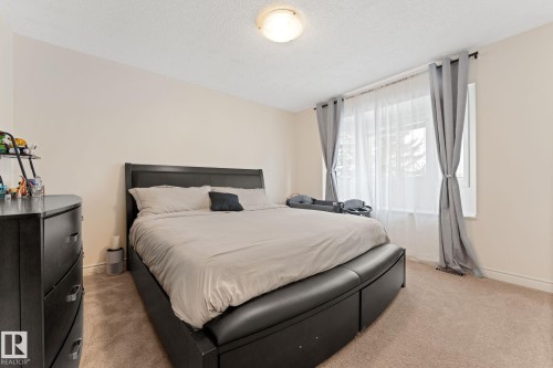 This bedroom features light-colored walls, carpeted flooring, and a window providing natural light - 7252 152C Avenue, Edmonton, AB - Indoor Photo Showing Bedroom