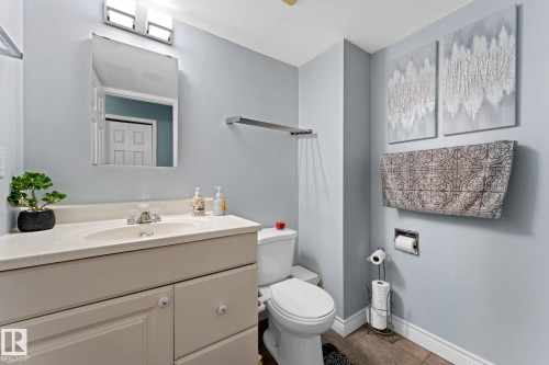 This bathroom features a vanity with a countertop and sink, a toilet, and light blue walls - 7252 152C Avenue, Edmonton, AB - Indoor Photo Showing Bathroom