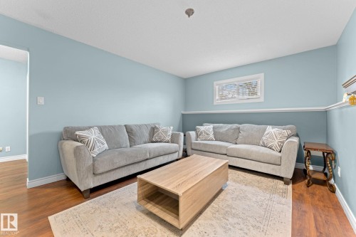 The living area features light blue walls with a white chair rail, hardwood flooring, and a window providing natural light - 7252 152C Avenue, Edmonton, AB - Indoor Photo Showing Living Room
