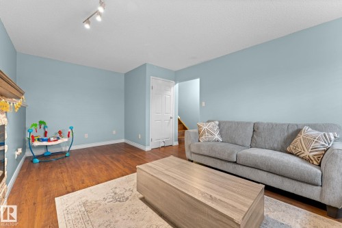 The living area features hardwood style flooring, light blue walls, and a white ceiling with track lighting - 7252 152C Avenue, Edmonton, AB - Indoor Photo Showing Living Room