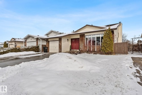 The property features a light-colored exterior with a brown roof and a red front door - 7252 152C Avenue, Edmonton, AB - Outdoor With Facade