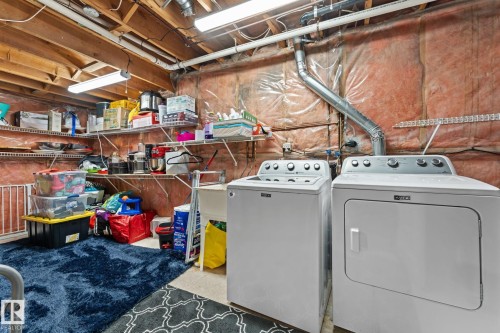 The property features a dedicated laundry area with a washer and dryer, exposed ceiling joists, and overhead lighting - 7252 152C Avenue, Edmonton, AB - Indoor Photo Showing Laundry Room