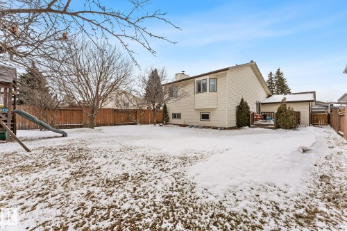 The property features a spacious rear yard with a wooden fence and mature trees - 7252 152C Avenue, Edmonton, AB - Outdoor