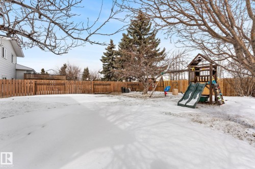The property features an expansive yard with a wooden fence and mature trees - 7252 152C Avenue, Edmonton, AB - Outdoor