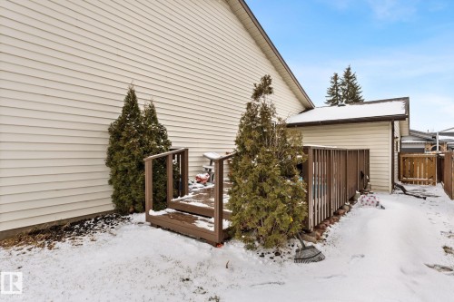 The exterior of the property features horizontal siding, a wooden deck, and established evergreen trees - 7252 152C Avenue, Edmonton, AB - Outdoor With Exterior