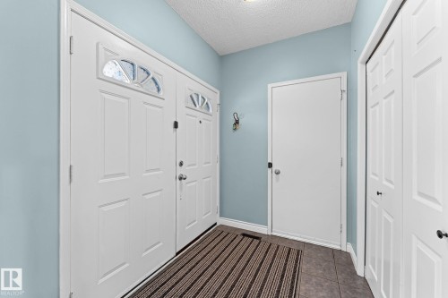 Entryway featuring a double door with decorative glass inserts, light blue wall paint, and tiled flooring - 7252 152C Avenue, Edmonton, AB - Indoor Photo Showing Other Room