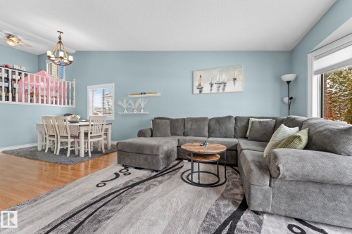The property features a living area with light blue walls, hardwood flooring, and a large window offering exterior views - 7252 152C Avenue, Edmonton, AB - Indoor Photo Showing Living Room