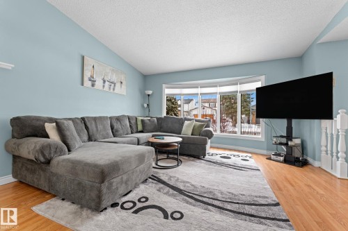 The living area features hardwood floors and a large bay window, providing natural light and views of the exterior - 7252 152C Avenue, Edmonton, AB - Indoor Photo Showing Living Room