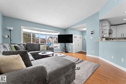 Living area featuring hardwood flooring, a large bay window, and light blue walls - 7252 152C Avenue, Edmonton, AB - Indoor Photo Showing Living Room
