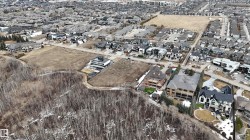 Aerial view of the neighborhood showcasing surrounding properties and undeveloped land - 