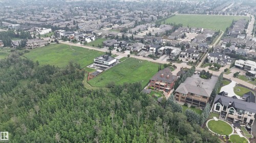 Aerial perspective showcasing a residential area bordered by dense tree coverage and expansive green spaces - 24 Windermere Drive Sw, Edmonton, AB 