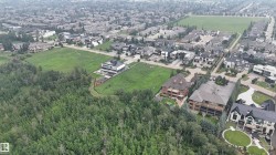 Aerial perspective showcasing a residential area bordered by dense tree coverage and expansive green spaces - 