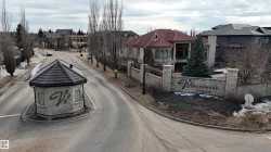 The property is situated within a community featuring a stone entrance monument with a distinct sign and a stone guardhouse with a dark roof - 
