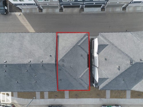 Aerial view of the property, showcasing its grey shingle roof and the surrounding street and sidewalk - 42 Corner Glen Manor Ne, Calgary, AB - 