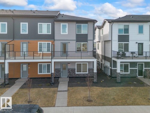 Modern townhome with a multi-level facade featuring varied siding materials and a balcony with a glass railing - 42 Corner Glen Manor Ne, Calgary, AB - Outdoor With Balcony With Facade