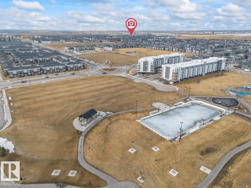 An aerial view showcasing the community with residential properties, a recreational field, and a paved pathway system - 42 Corner Glen Manor Ne, Calgary, AB - Outdoor With View
