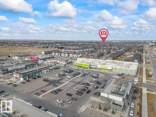 The area features commercial properties with various businesses, large parking lots, and residential properties in the background - 42 Corner Glen Manor Ne, Calgary, AB - Outdoor With View