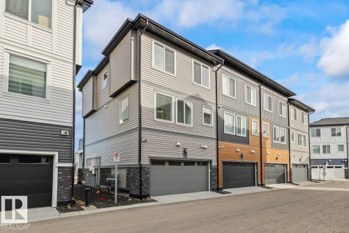 The property features a modern exterior with horizontal siding and a dark garage door - 42 Corner Glen Manor Ne, Calgary, AB - Outdoor