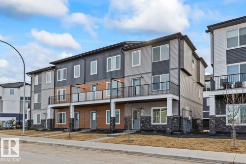 The property features a modern exterior with varied siding, encompassing horizontal siding, vertical panels, and stone detailing - 42 Corner Glen Manor Ne, Calgary, AB - Outdoor With Balcony With Facade