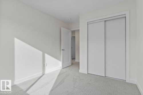 This room features light-colored walls, patterned carpeting, and a closet with sliding doors - 42 Corner Glen Manor Ne, Calgary, AB - Indoor Photo Showing Other Room