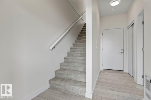 Entryway featuring light-toned flooring, a staircase with carpeted treads, and a modern flush-mount ceiling light - 42 Corner Glen Manor Ne, Calgary, AB - Indoor Photo Showing Other Room