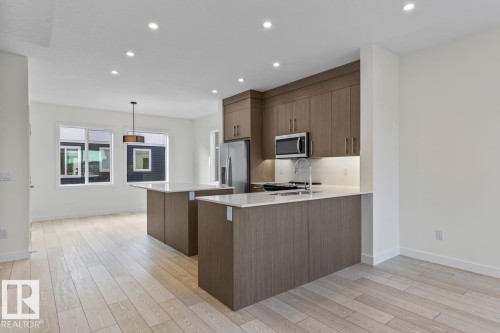 The kitchen features modern cabinetry, stainless steel appliances, and two central islands with white countertops - 42 Corner Glen Manor Ne, Calgary, AB - Indoor Photo Showing Kitchen With Upgraded Kitchen