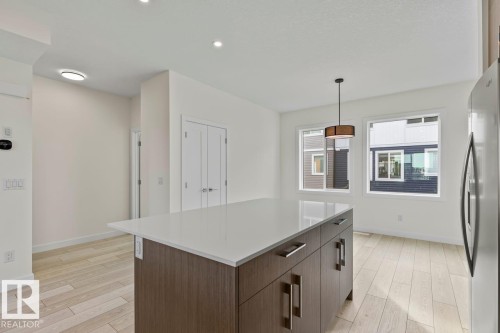 Modern kitchen featuring a central island with a light-colored countertop, recessed lighting, and light wood-style flooring - 42 Corner Glen Manor Ne, Calgary, AB - Indoor Photo Showing Kitchen