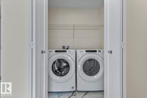 Dedicated laundry area with a washer and dryer, featuring a wire shelf for storage and a tiled floor - 42 Corner Glen Manor Ne, Calgary, AB - Indoor Photo Showing Laundry Room